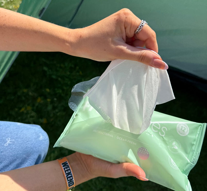 Camper opening ocean freshwipes outside a tent