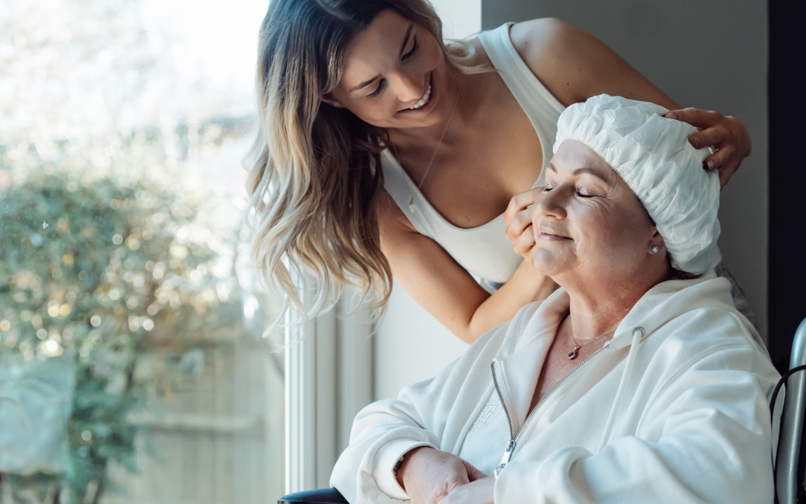 carer helping woman use shampoo cap